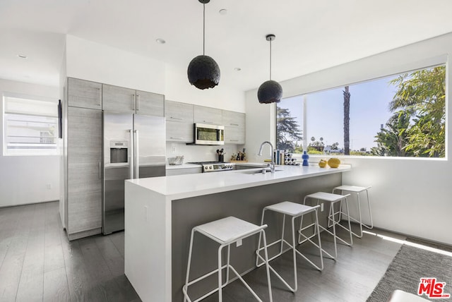 kitchen featuring appliances with stainless steel finishes, a kitchen bar, plenty of natural light, and decorative light fixtures