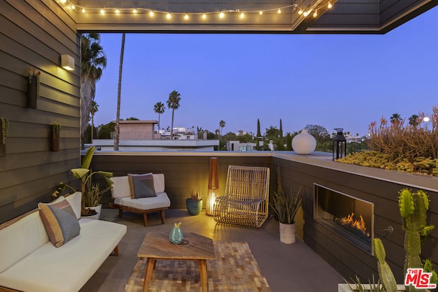 patio terrace at dusk with outdoor lounge area and a balcony