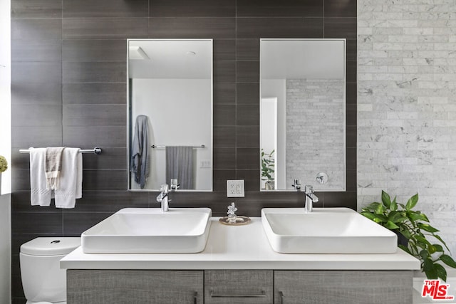 bathroom with toilet, tile walls, and vanity