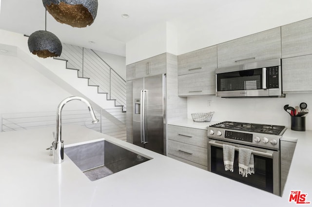 kitchen with appliances with stainless steel finishes, hanging light fixtures, and sink