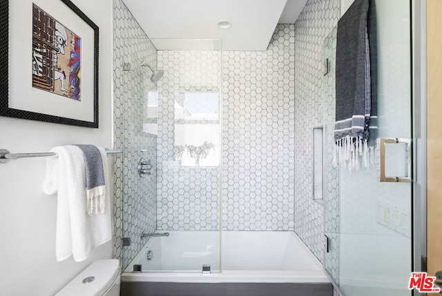 bathroom featuring combined bath / shower with glass door and toilet