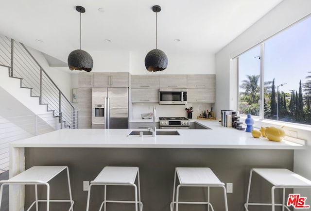 kitchen with stainless steel appliances, sink, hanging light fixtures, kitchen peninsula, and a breakfast bar area