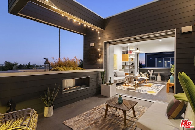 patio terrace at dusk featuring an outdoor living space with a fireplace