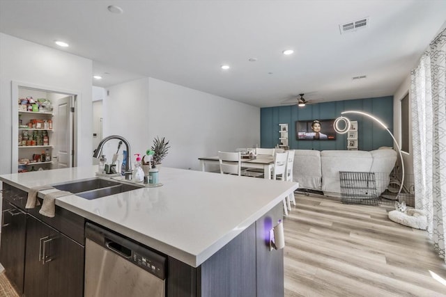 kitchen featuring stainless steel dishwasher, dark brown cabinetry, sink, a center island with sink, and light hardwood / wood-style floors