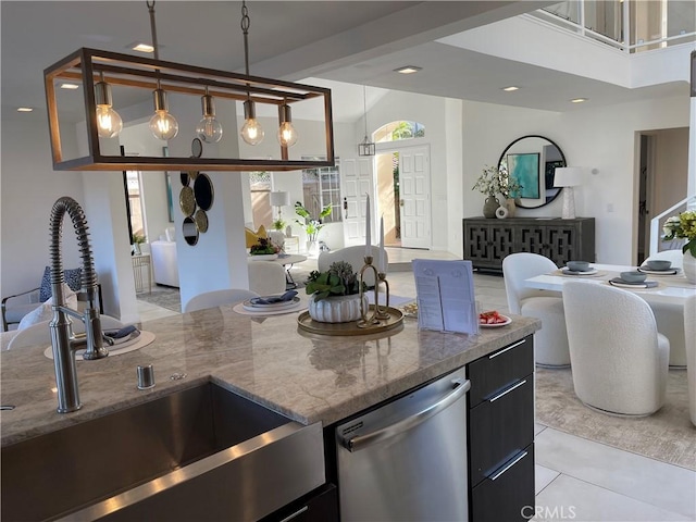 kitchen featuring dishwasher, sink, light stone counters, decorative light fixtures, and light tile patterned floors