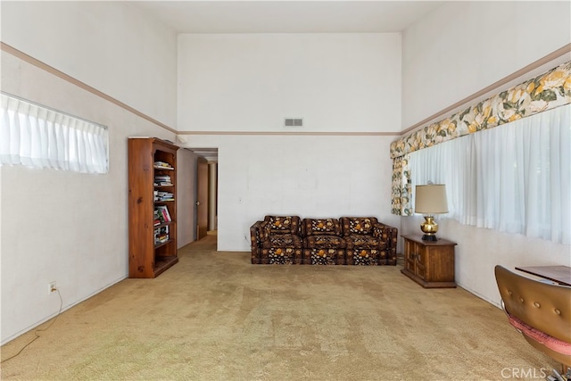 living area with light carpet and a high ceiling