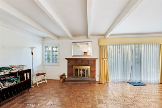 living room featuring beamed ceiling and a brick fireplace