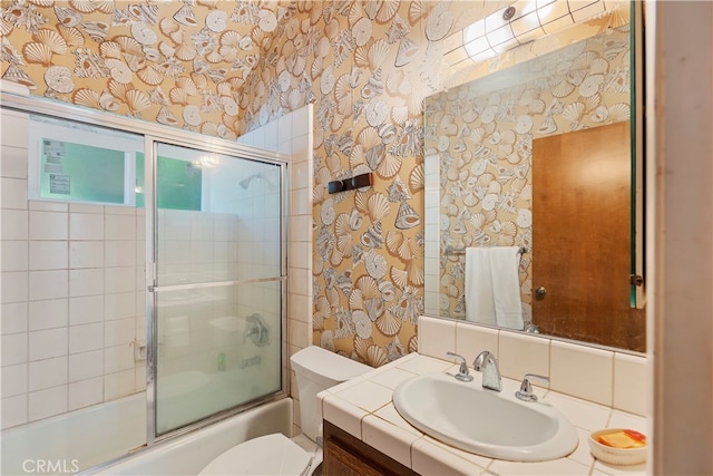 full bathroom featuring vanity, toilet, and bath / shower combo with glass door