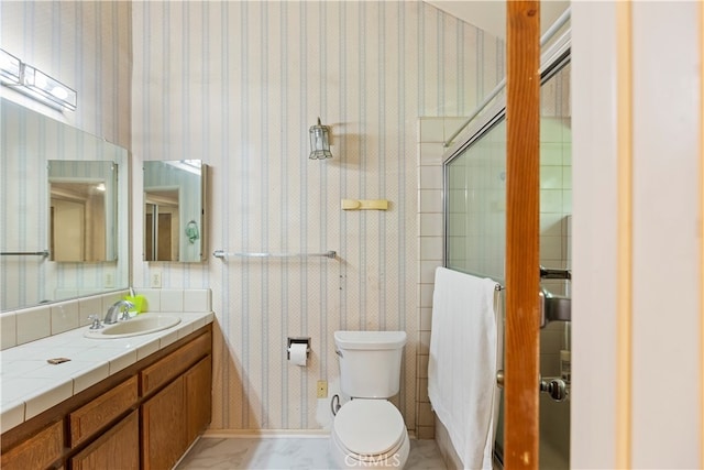 bathroom featuring vanity, a shower with shower door, and toilet