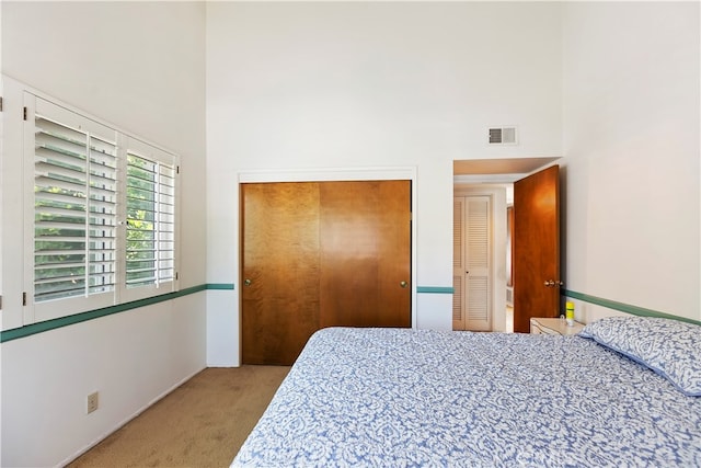 bedroom with a closet, light carpet, and a high ceiling