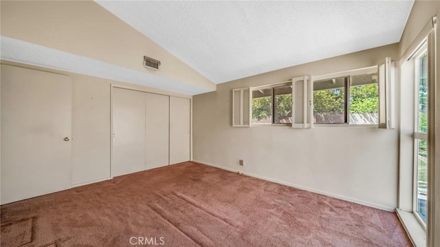 unfurnished bedroom with a closet, carpet, and vaulted ceiling