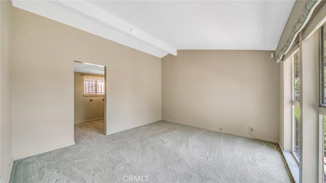 empty room with vaulted ceiling with beams and light colored carpet