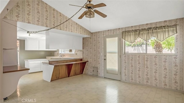 kitchen featuring white cabinetry, sink, ceiling fan, kitchen peninsula, and vaulted ceiling