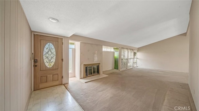 carpeted entryway featuring a textured ceiling and vaulted ceiling