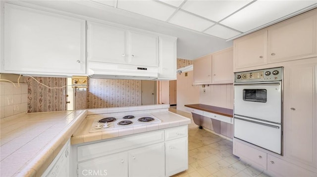 kitchen with white cabinets, white appliances, tile counters, and backsplash