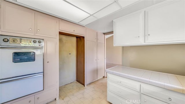 kitchen with white cabinetry, tile counters, and oven