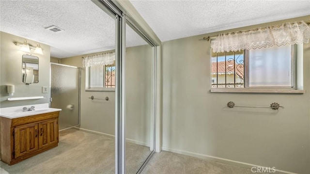 bathroom with vanity, a textured ceiling, and walk in shower