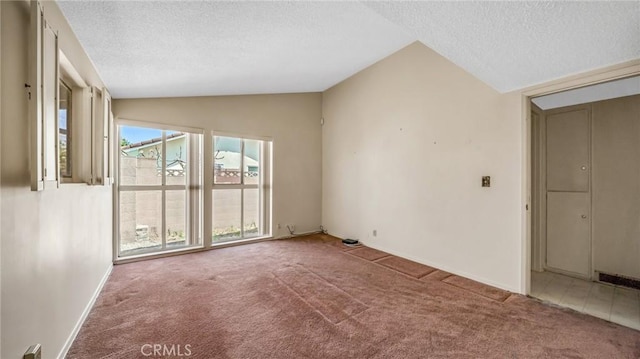 carpeted empty room with a textured ceiling and vaulted ceiling