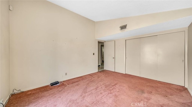 unfurnished bedroom featuring carpet flooring, vaulted ceiling, and a closet