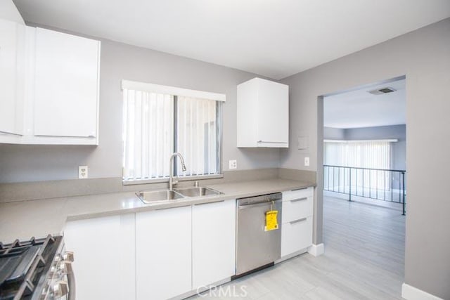 kitchen featuring appliances with stainless steel finishes, light hardwood / wood-style floors, sink, and white cabinets