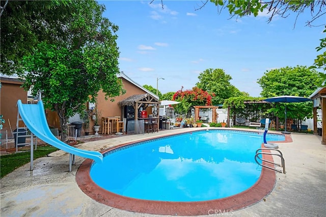 view of swimming pool with a water slide, a diving board, and a patio area