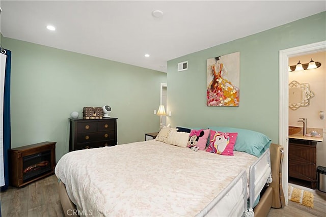 bedroom with ensuite bathroom and light hardwood / wood-style floors