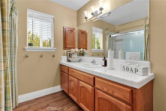 bathroom with hardwood / wood-style floors, vanity, and a shower