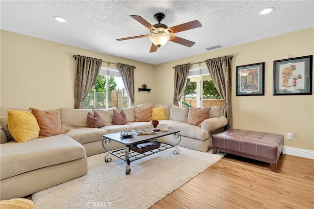 living room with a textured ceiling, light hardwood / wood-style floors, and ceiling fan