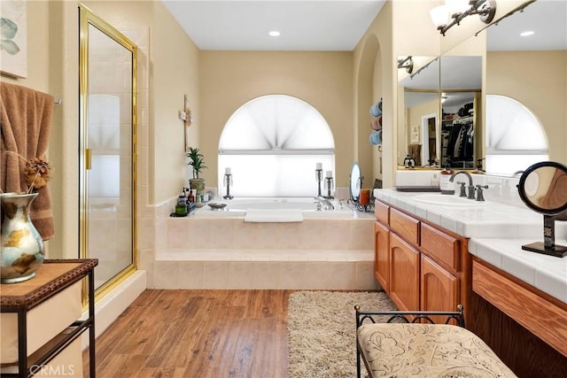 bathroom featuring plus walk in shower, vanity, hardwood / wood-style flooring, and a wealth of natural light