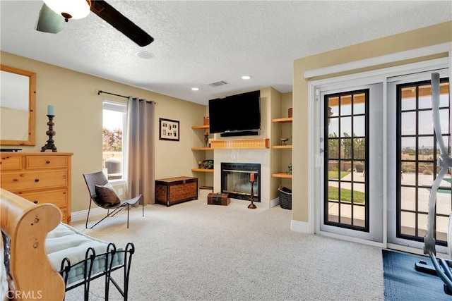 carpeted living room with ceiling fan and a textured ceiling