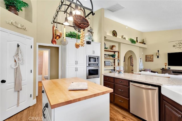 kitchen with butcher block counters, dark brown cabinetry, a kitchen island, white cabinets, and appliances with stainless steel finishes