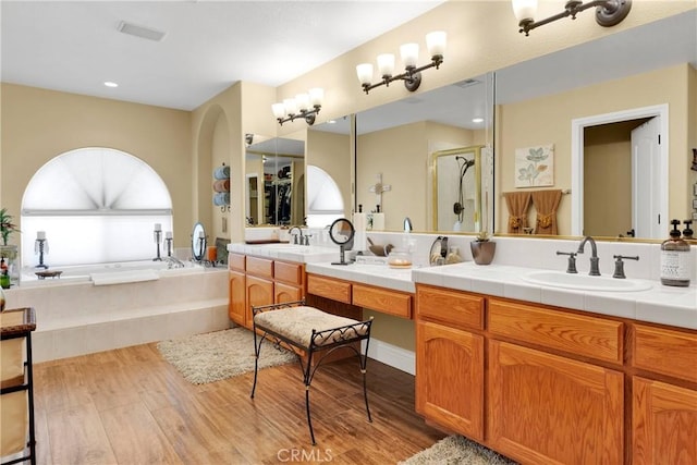 bathroom featuring plus walk in shower, wood-type flooring, and vanity