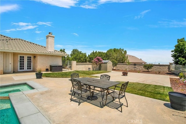 view of patio featuring a pool with hot tub, a storage shed, central air condition unit, and french doors