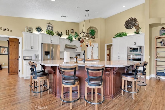 kitchen with a large island, a breakfast bar, white cabinets, and stainless steel appliances