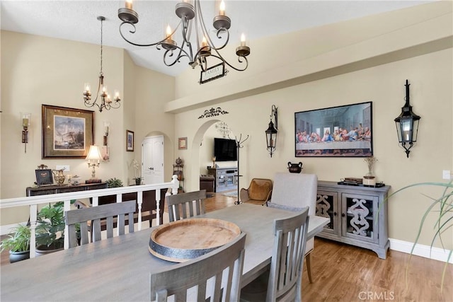 dining room featuring hardwood / wood-style flooring, vaulted ceiling, and a notable chandelier