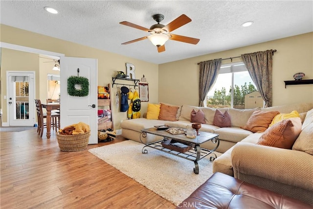 living room featuring a textured ceiling, light wood-type flooring, and ceiling fan