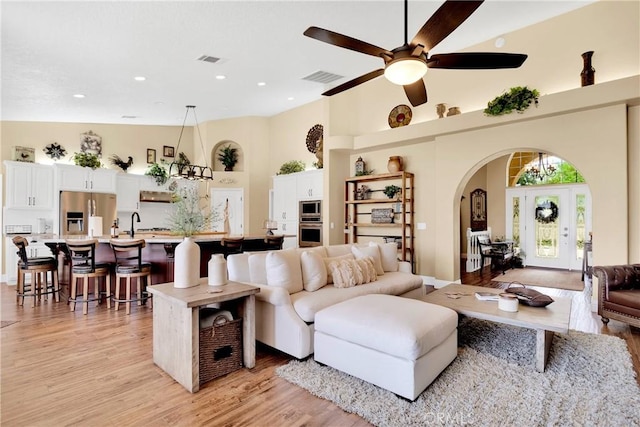 living room featuring a high ceiling, light hardwood / wood-style flooring, ceiling fan, and sink