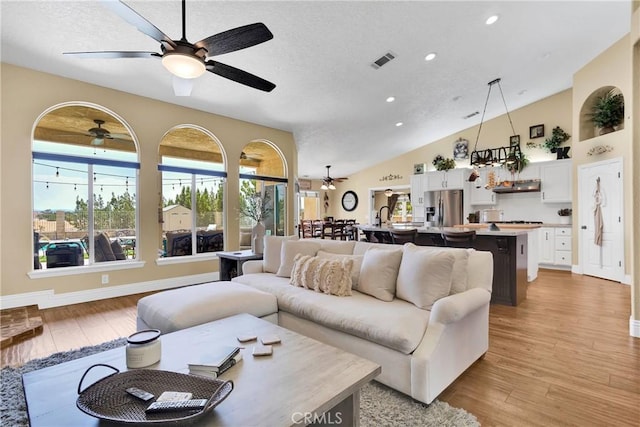 living room with a healthy amount of sunlight, light hardwood / wood-style floors, and vaulted ceiling