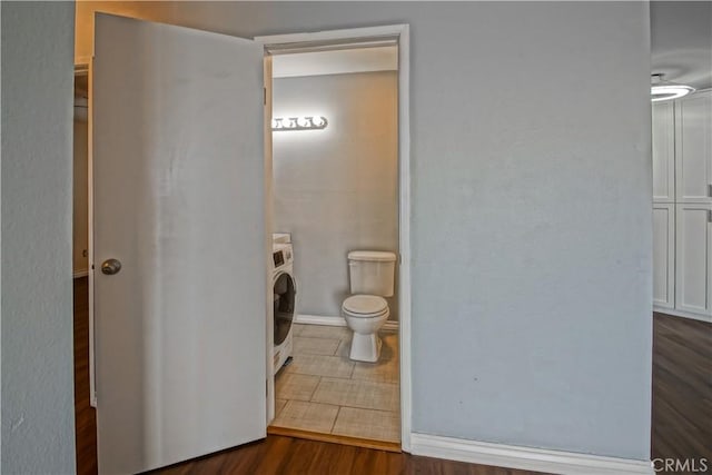 bathroom with toilet, washer / dryer, and wood-type flooring