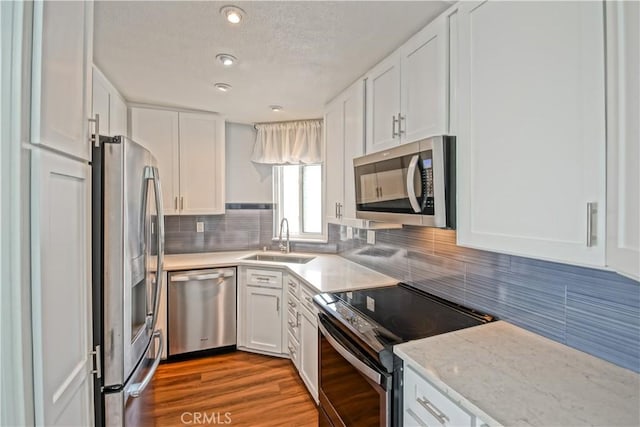 kitchen with white cabinets, sink, light hardwood / wood-style flooring, appliances with stainless steel finishes, and tasteful backsplash