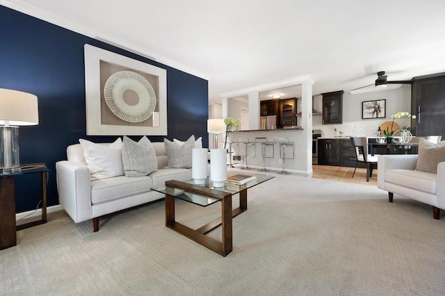 living room featuring ceiling fan, light colored carpet, and ornamental molding