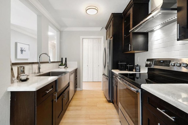 kitchen with wall chimney exhaust hood, crown molding, sink, and appliances with stainless steel finishes