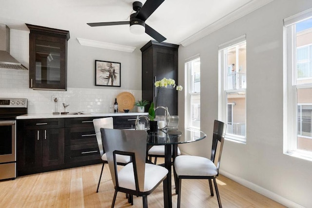 kitchen with wall chimney exhaust hood, tasteful backsplash, electric stove, ceiling fan, and crown molding