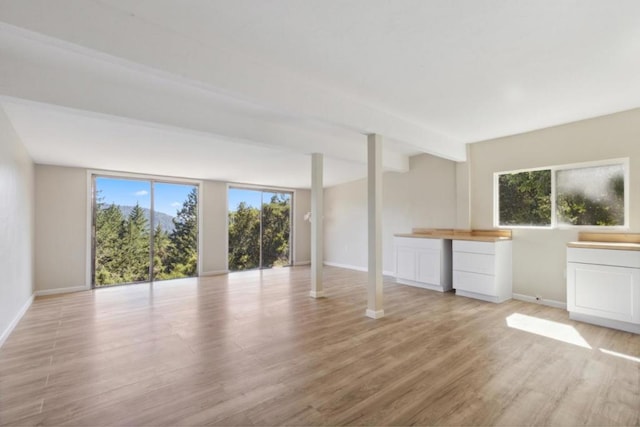 unfurnished room with light hardwood / wood-style flooring and beam ceiling