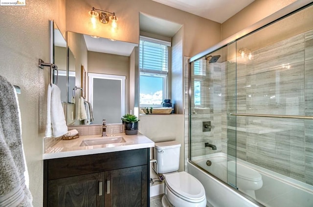 full bathroom featuring vanity, toilet, and bath / shower combo with glass door