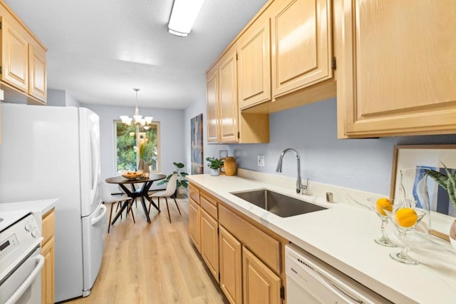 kitchen with light brown cabinetry, light hardwood / wood-style floors, an inviting chandelier, and sink