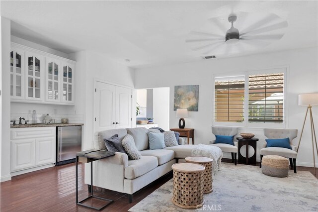 living room with dark wood-type flooring, ceiling fan, and wet bar