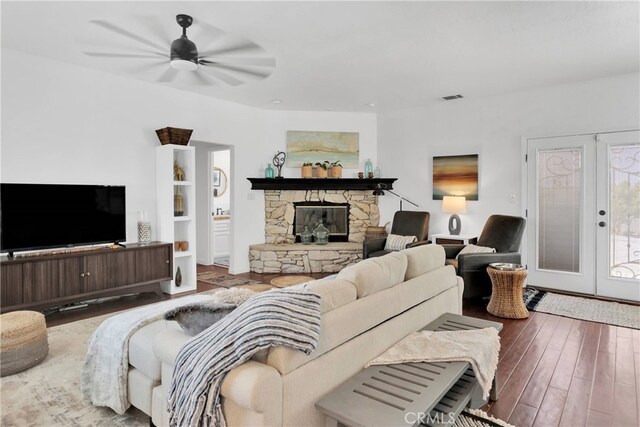 living room featuring ceiling fan, a fireplace, and wood-type flooring