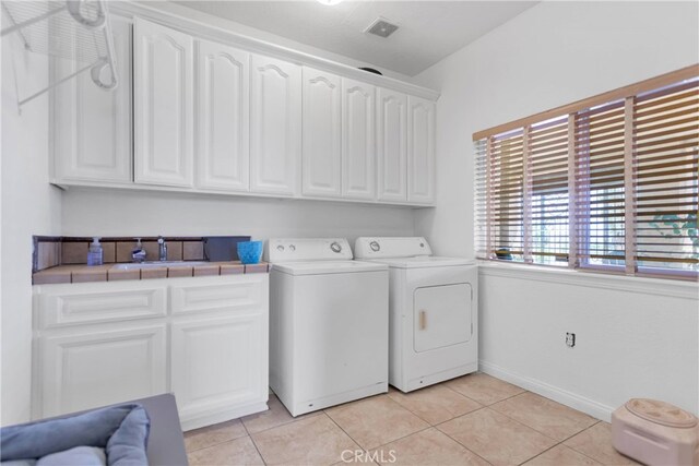 laundry area with cabinets, independent washer and dryer, and light tile patterned flooring