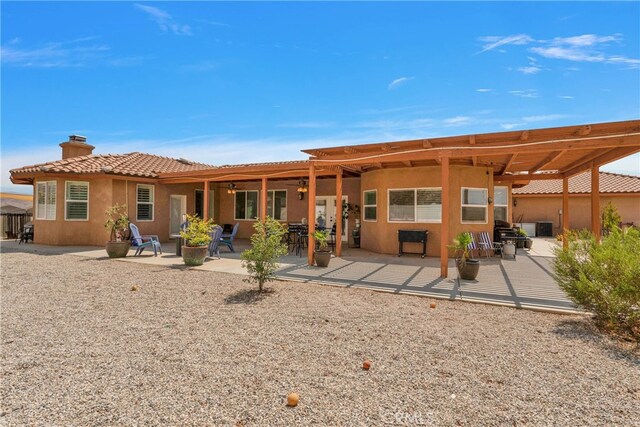 rear view of property featuring a pergola and a patio area